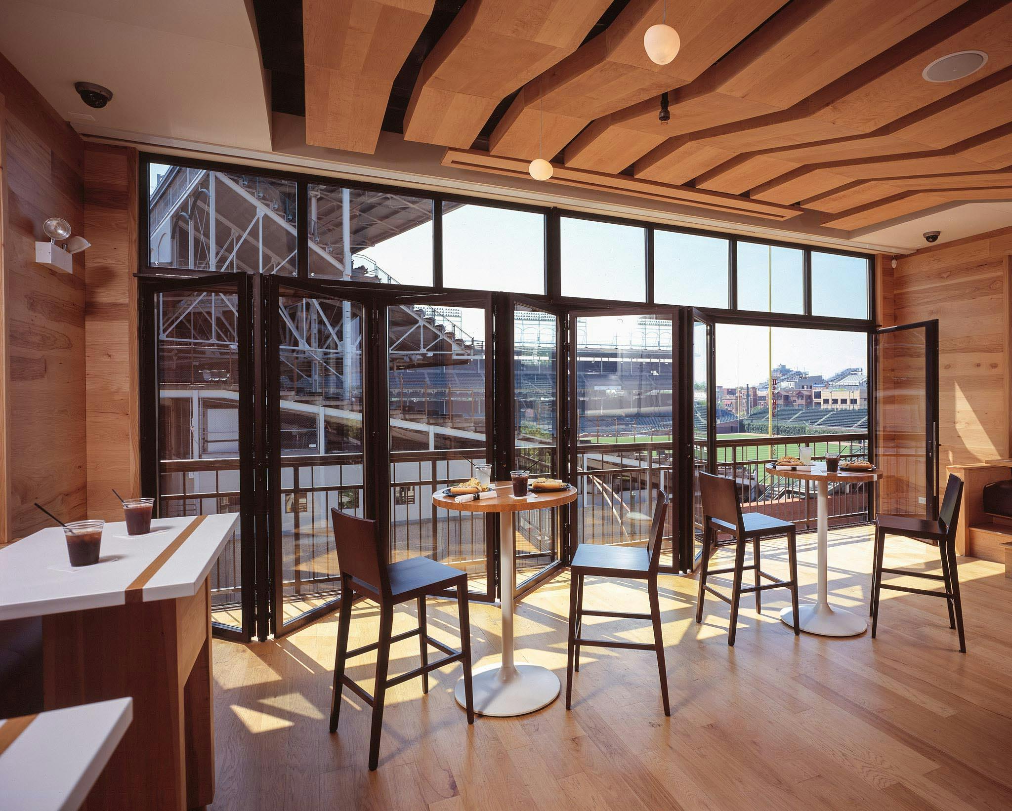 commercial folding glass wall system partially open with view of baseball view for live games